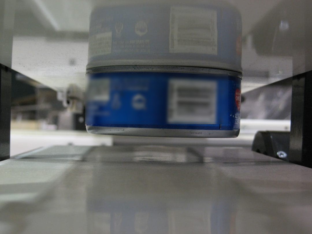 Steel can held magnetically against the underside of a conveyor belt