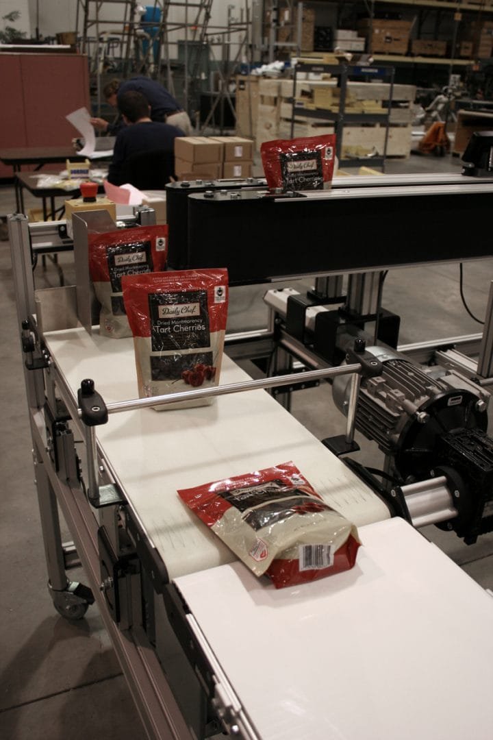 Settling conveyor levelling filled pouches before packing