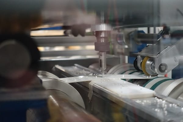 Sheet material carried on a vacuum conveyor